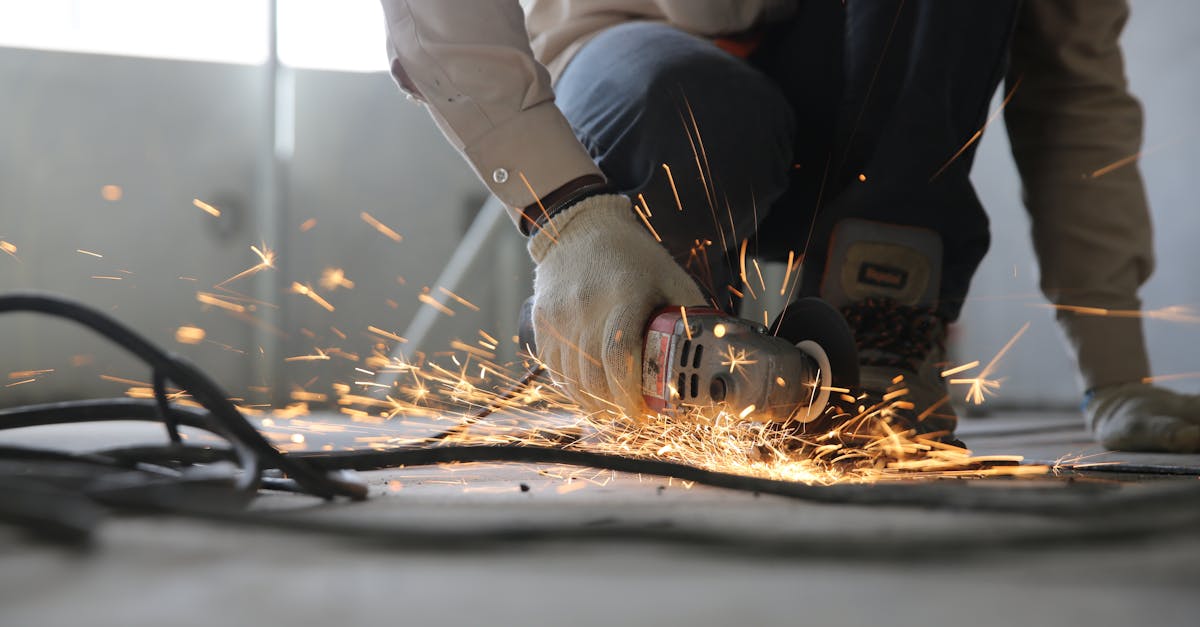 A skilled industrial worker uses a grinder creating a burst of sparks indoors.