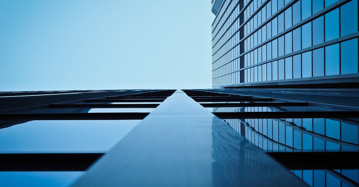 Low angle view of a modern skyscraper with reflective glass facade and blue sky.