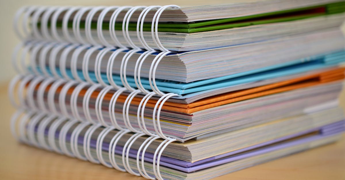 A colorful stack of spiral-bound notebooks neatly placed on a wooden desk. Ideal for educational themes.