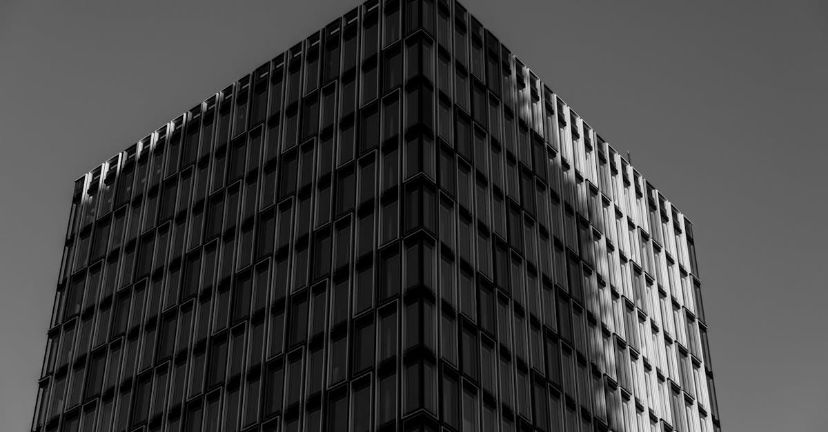 Black and white photo of modern skyscraper facade with reflective windows.