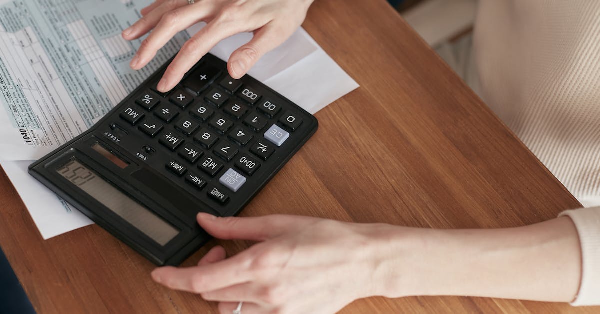 Close-up of a woman using a calculator and reviewing bills at home.