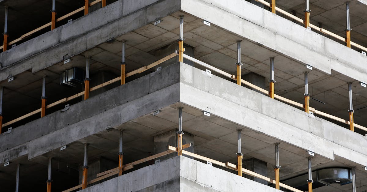 Close-up of an unfinished multi-level concrete building with steel reinforcements.